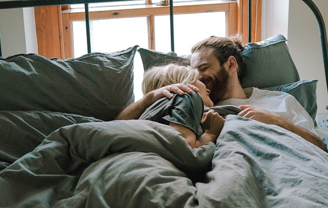 a man kissing the forehead of a woman while they lay in bed
