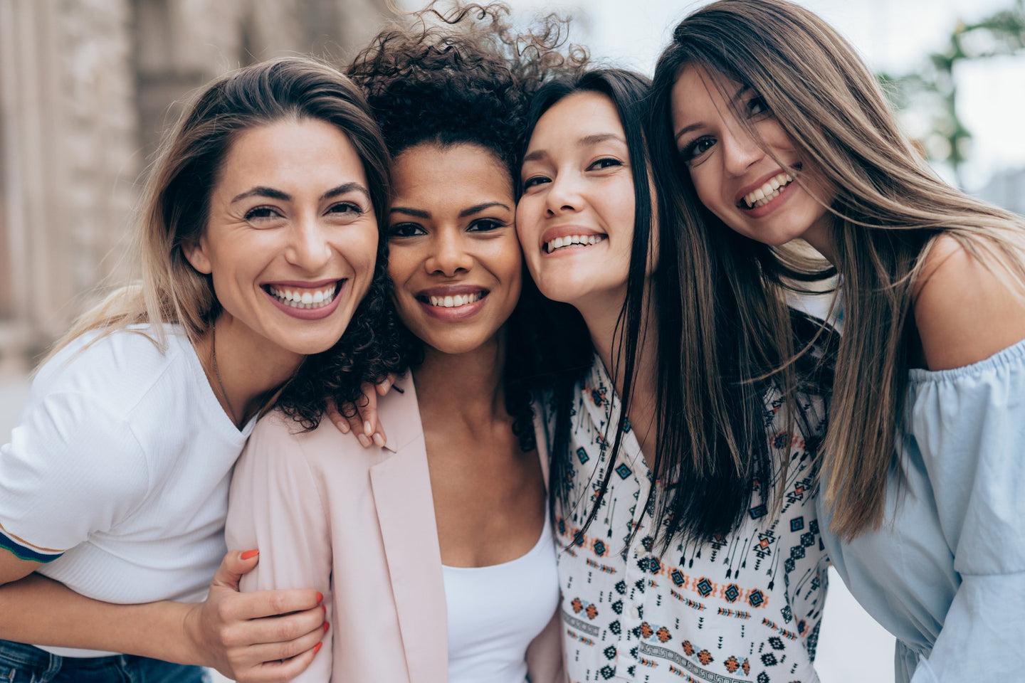 Four women together outdoors, smiling.