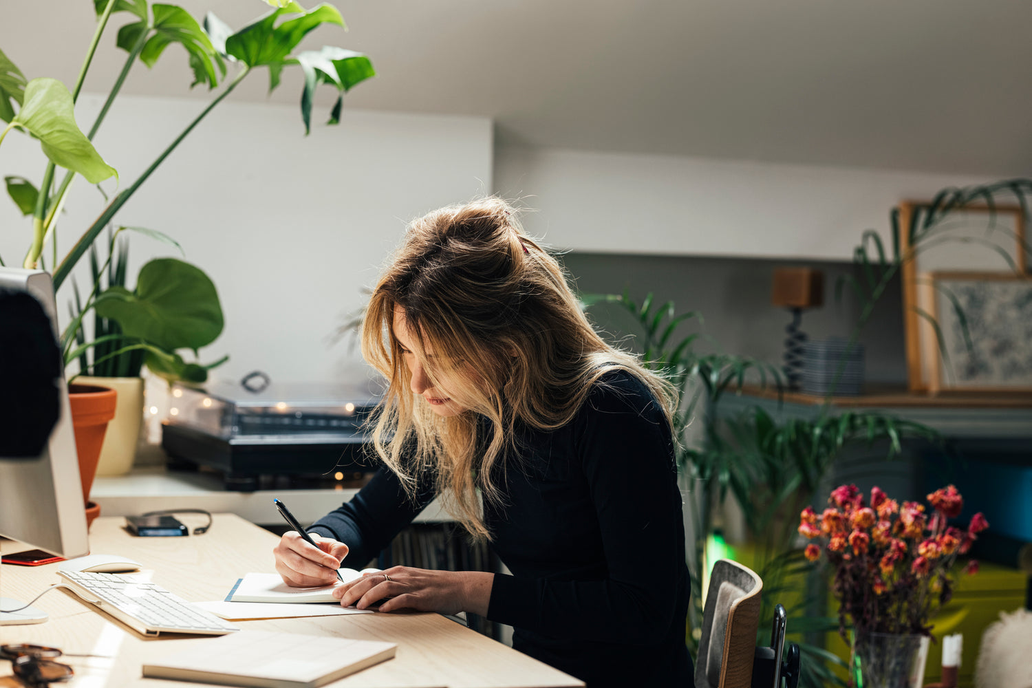 A woman writing in a journal or book at her desk