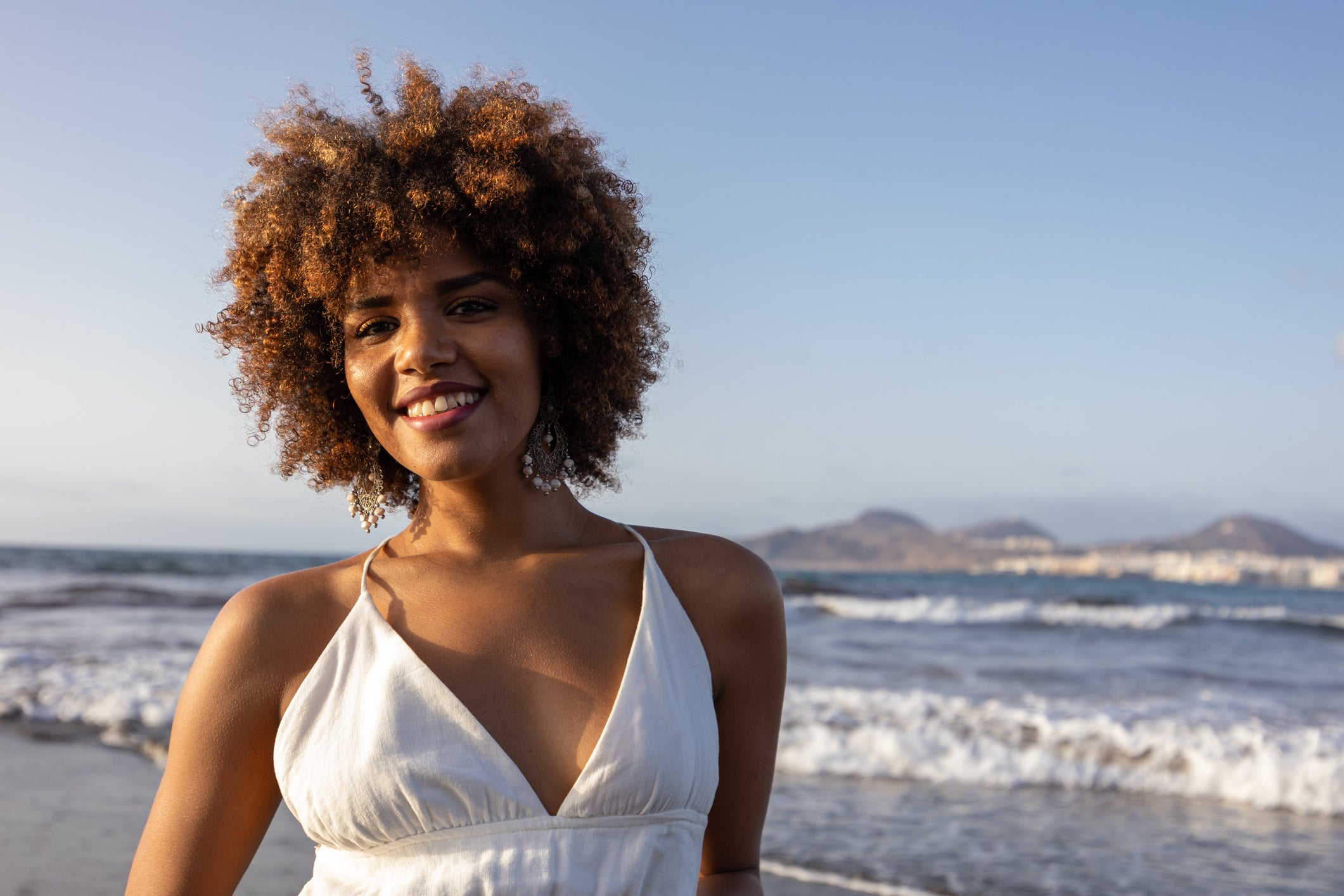 A smiling woman at the beach looking at the camera
