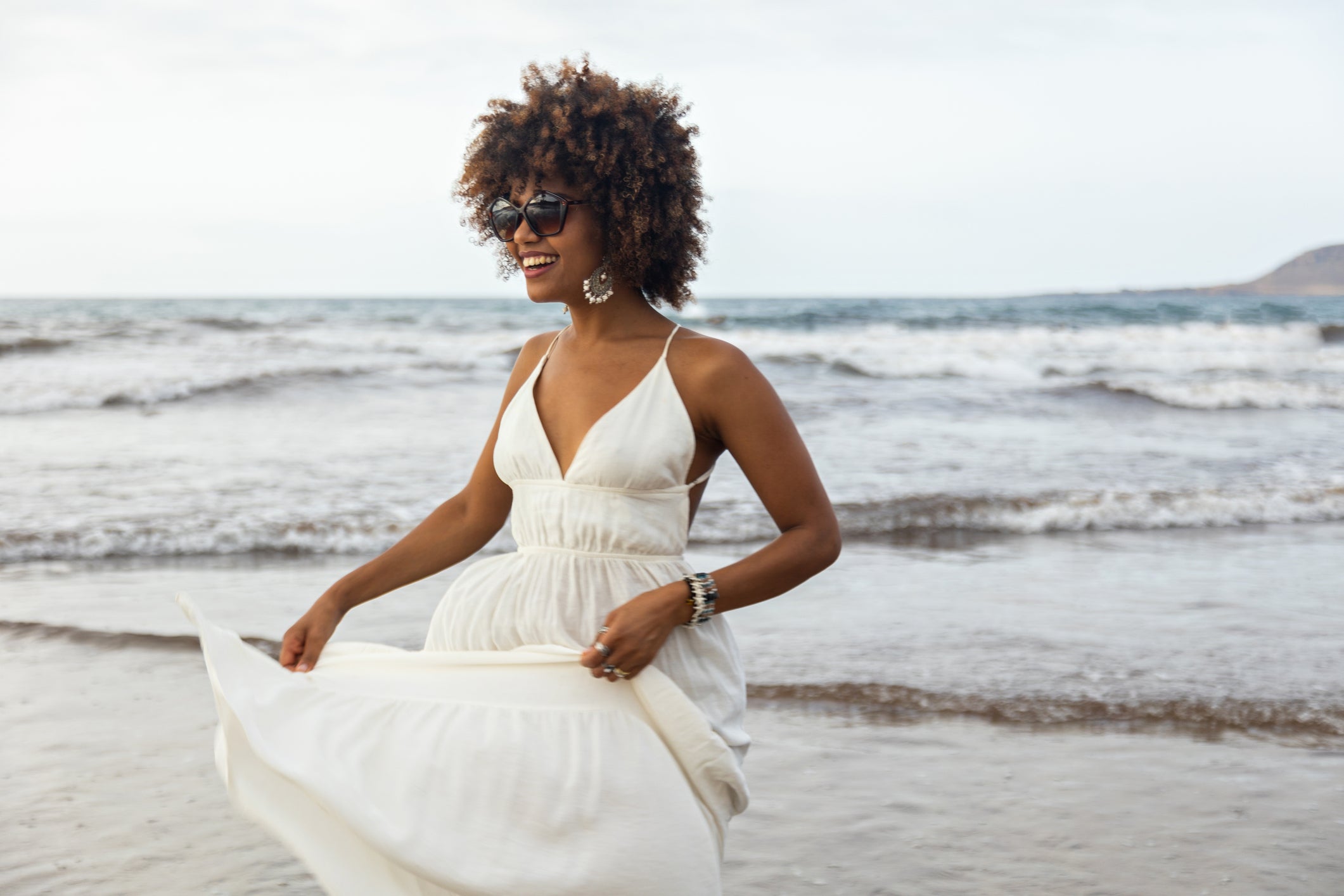 A happy woman in a white dress at the beach